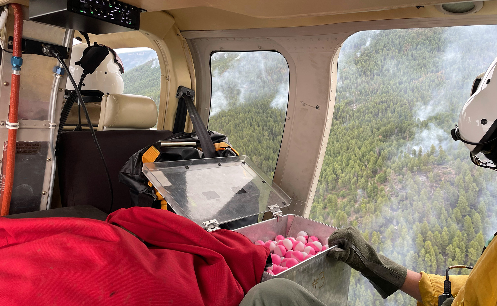 Firefighter operates a plastic sphere dispenser from a helicopter.