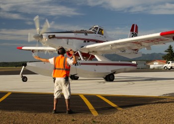 An airfield worker directing a firefighting plane on tarmac