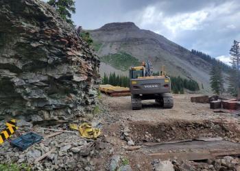 Job Corp staff use heavy equipment to replace a culvert on a mountain road