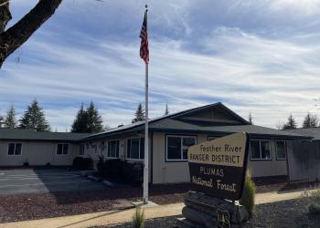 Photo of Feather River Ranger District front office with flag and forest sign.